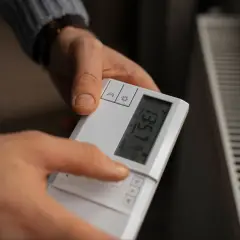 Ręce ustawiają sterownik pieca gazowego. Na ekranie widoczna jest temperatura 16.0°C.