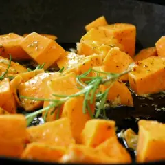 Pokrojone bataty w kostkę, doprawione ziołami i czosnkiem, smażone na patelni. Idealne, by dowiedzieć się, jak zrobić bataty na obiad.