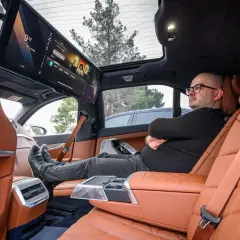 Wnętrze BMW i6 z ekranem multimedialnym dla pasażerów. Mężczyzna relaksuje się na tylnym siedzeniu.