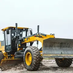 Żółta równiarka do drogi pracuje na budowie, wyrównując teren.