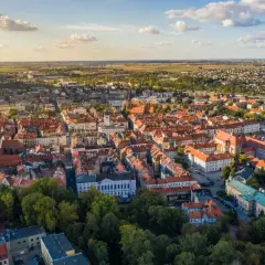 Widok z lotu ptaka na zabytkowe centrum Kalisza, najstarszego miasta w Polsce, z charakterystyczną czerwoną dachówką i zielenią drzew.