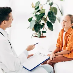 Lekarz rozmawia z uśmiechniętą dziewczynką o jej ADHD. Leczenie może przynieść ulgę i poprawić jakość życia.