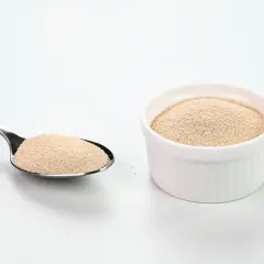 Levure sèche dans une cuillère et un ramequin blanc. Comprendre la différence entre levure chimique et bicarbonate de soude est essentiel pour la pâtisserie.