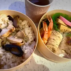 A delicious ekiben, meaning train bento, with rice, chicken, mushrooms, shrimp, and other treats, perfect for a journey.