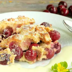 Zwei Portionen Kirschenmichel, ein köstliches Dessert, serviert mit Vanillesauce und bestäubt mit Puderzucker. Ein perfektes Kirschenmichel Rezept.
