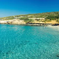 En solig strand med turkost vatten och människor som badar. En perfekt dag att se på Kreta.
