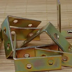 Stos różnych rodzajów kątowników metalowych, gotowych do wzmocnienia konstrukcji.
