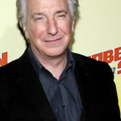 Alan Rickman, uśmiechnięty, w czarnym garniturze, na tle napisu "BEL SON". Może wspominał swoje dzieciństwo?