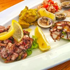 Pyszne dania chorwackie: sałatka z ośmiornicy, krewetki, małże i carpaccio z ryby, ozdobione cytryną.