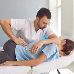 Fizjoterapeuta wykonuje terapię manualną, uciskając plecy pacjentki. To pokazuje, na czym polega terapia manualna – na pracy z ciałem.