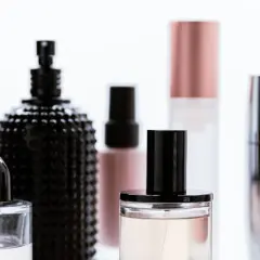 Eleganckie flakony kosmetyków, w tym jeden z czarną, fakturowaną powierzchnią. Wiele z nich zawiera płyny, sugerując zastosowanie olejów mineralnych w kosmetykach.