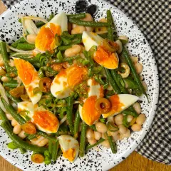 Ensalada de judías verdes, huevos duros, alubias blancas y aceitunas, aderezada con cebolleta picada.
