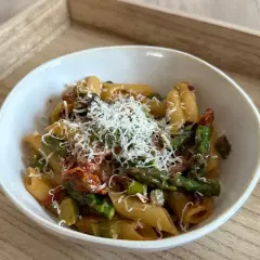 Penne z zielonymi szparagami i suszonymi pomidorami w kremowym sosie, posypane parmezanem. Pyszny makaron ze szparagami w sosie śmietanowym.