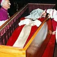 Würdenträger bei der Umbettung von Johannes Paul II. im Sarg, der mit rotem Stoff und weißen Bändern geschmückt ist.
