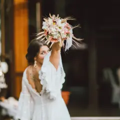 Panna młoda w białej sukni z bukietem w dłoni, radośnie spogląda przez ramię. To symboliczny moment, który przypomina o tradycji oczepin.