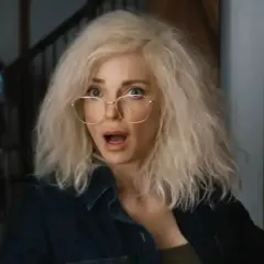 Kobieta z blond włosami i okularami, przerażona, jakby oglądała straszny film 6. W tle monitory.