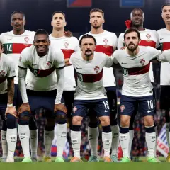 Drużyna piłkarzy Portugalii w białych strojach z czerwonym pasem, gotowa do meczu.