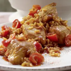 Serbisches Reisfleisch mit zarten Fleischstücken und Tomaten, serviert auf einem weißen Teller.