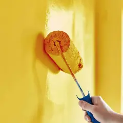 Malowanie żółtej ściany wałkiem. Zastanawiasz się, ile schnie farba ceramiczna? Czas schnięcia zależy od wielu czynników.