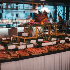 Ett dignande julbord med charkuterier, en dekorerad grisbuk och en bar i bakgrunden. En festlig Mister French julbord-upplevelse.