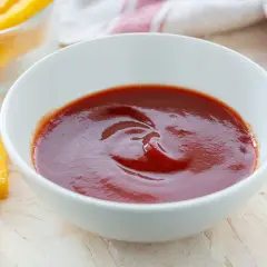 Ciotola di ketchup fatto in casa, con bastoncini di polenta fritta intorno.