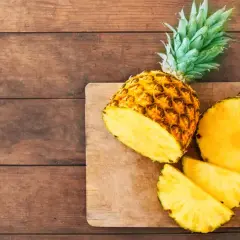 Saftige Ananas, frisch aufgeschnitten, liegt auf einem Holzbrett. Eine gesunde Wahl, die an den Geschmack von Ananas aus der Dose erinnert.