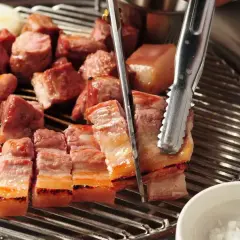 Pyszny boczek na grilla, idealny do marynaty. Kawałki mięsa skwierczą na ruszcie, gotowe do podania.