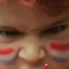 Niño con pintura facial de bandera, con mirada intensa, como si temiera el mal de ojo.