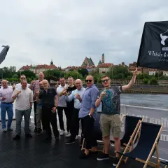 Grupa mężczyzn świętuje na statku, unosząc kieliszki. Czy warto inwestować w whisky kolekcjonerską? Portfel inwestycyjny 2026.