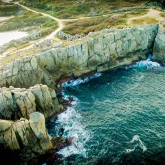 Impresionantes acantilados galicia, con el mar azul turquesa rompiendo contra las rocas. Senderos serpentean por la vegetación verde.