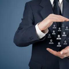 Biznesmen w garniturze chroni dłońmi grupę ikon ludzi.