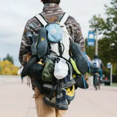 A climber's backpack is laden with multiple pairs of climbing shoes, a testament to a day of ascents.