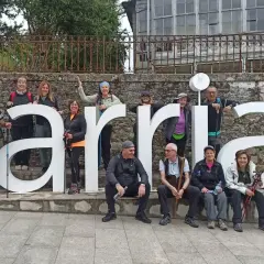 Grupo de peregrinos posa frente a las letras gigantes de Sarria, final de su **tren Santiago Sarria**.