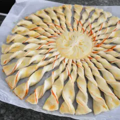 Tarte soleil prête à cuire, avec sa pâte feuilletée torsadée et son centre décoré. Un délice visuel et gustatif.
