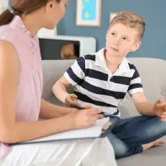 Psycholog rozmawia z chłopcem siedzącym na kanapie.