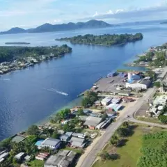Widok na zatokę z miasteczkiem na wybrzeżu, portem i łodzią. W oddali wyspy i góry. Bougainville.