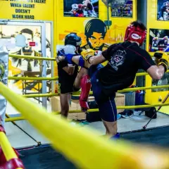 Two fighters practice kicks in a boxing ring, showcasing the intense benefits of sparring for skill development and conditioning.