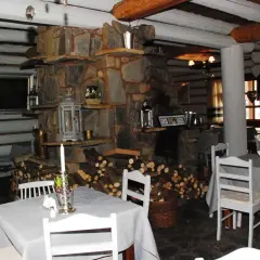 Przytulne bistro prosto z targu, z kamiennym kominkiem i drewnianymi belkami. Stoły nakryte szarymi obrusami, białe krzesła.