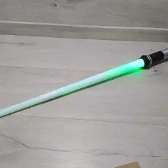 Zielony miecz Star Wars leży na drewnianej podłodze.