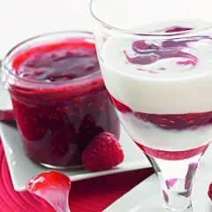 Sok z malin Thermomix w deserze jogurtowym. Słoiczek domowej konfitury malinowej obok.
