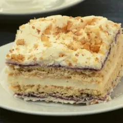 Pyszne ciasto z chałwą i serkiem mascarpone, przełożone kremem i dżemem, posypane orzechami.