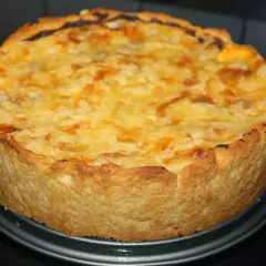 En gyllene, nybakad kycklingpaj med ostigt täcke, redo att avnjutas. En perfekt leilas kycklingpaj!
