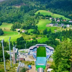 Malownicza panorama Wisły w górach. Widok na skocznię narciarską, wyciągi i zielone wzgórza z domkami.