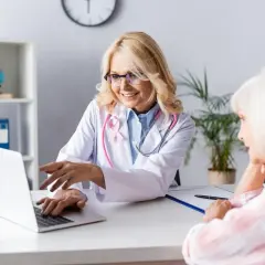 Lekarka z różową wstążką wyjaśnia pacjentce wyniki badań na laptopie. Czy to etruzil, czy to chemia? Ważne, że jest nadzieja.
