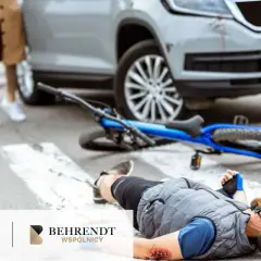 Wypadek w drodze do pracy: rowerzysta leży na pasach po zderzeniu z samochodem. Widoczne obrażenia i przewrócony rower.