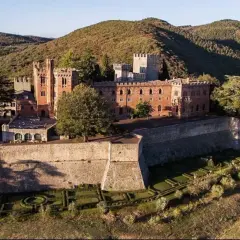 Il Castello di Brolio, imponente fortezza in mattoni rossi, domina le colline toscane, circondato da vigneti e cipressi.