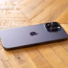 Nowy iPhone 14 Pro Max aparat z trzema obiektywami na drewnianym tle.