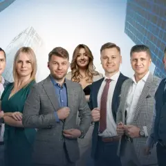 Grupa profesjonalistów w garniturach na tle nowoczesnych budynków.