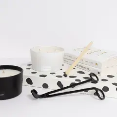Candle care essentials: two candles, a wick trimmer, matches, and books. Learn how to remove candle wax for a cleaner burn.