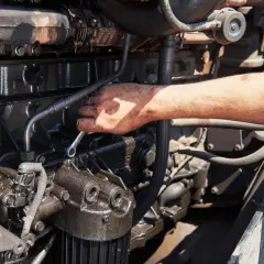 Mano che lavora su un motore, forse per riparare l'alternatore auto.
